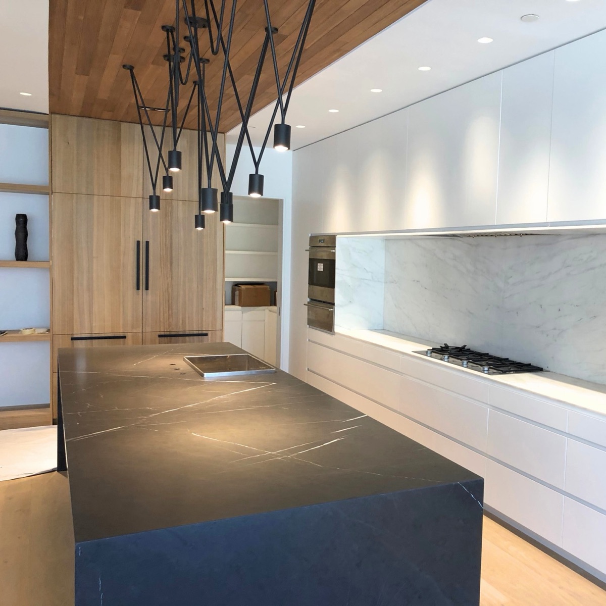 Honed dark stone island and marble backsplash in a contemporary kitchen with food-preparation surfaces treated with AntiEtch&reg;